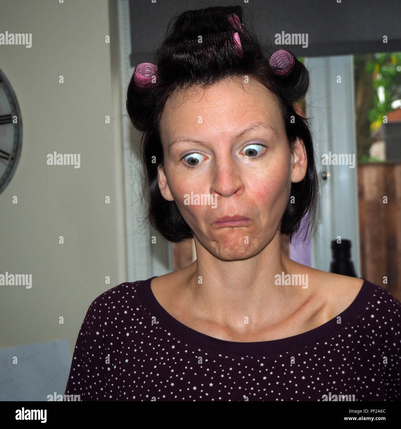 Woman pulling faces with curlers in her hair. Stock Photo