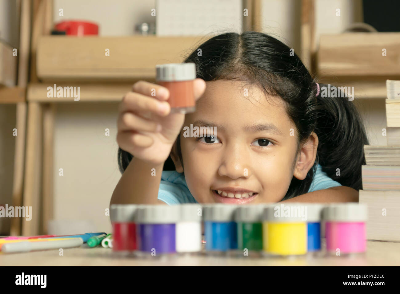 Little asian girl is showing a color and looking forward with smilling. Color group and book on the desk. Select focus shallow depth of field. Stock Photo