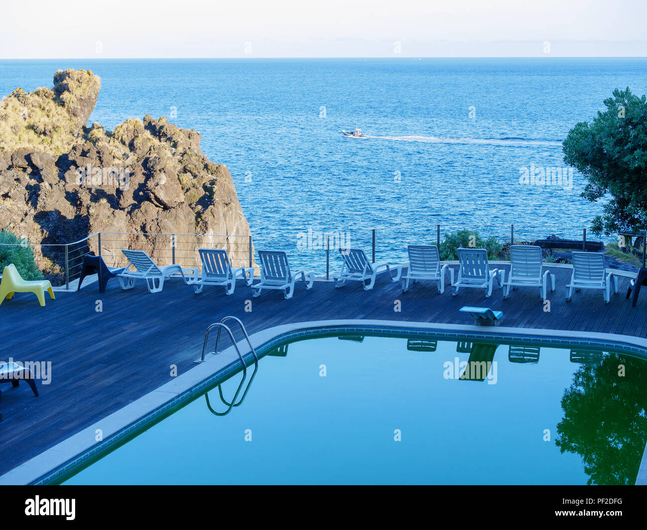 Wooden deck with swimming pool and sun beds and the sea in the