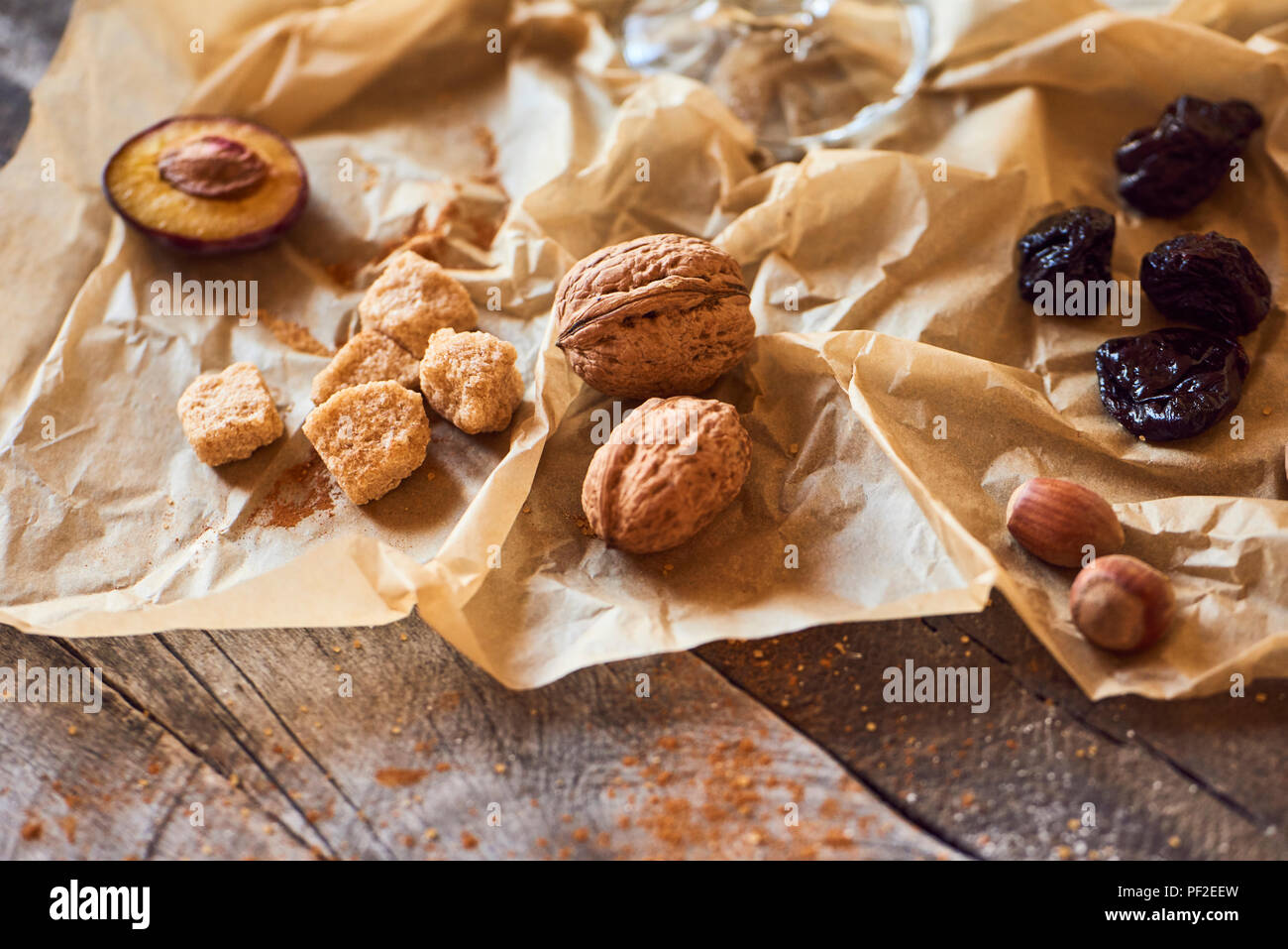 Dried plums, nuts, cinnamon and cane sugar on rustic background. Stock Photo