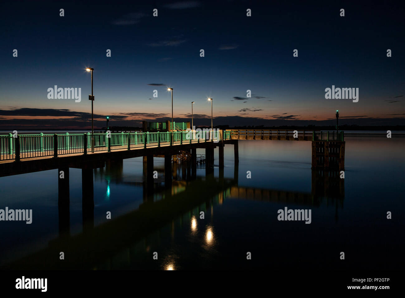 Pier at Caernarfon at dusk reflecting in the Menai Straits Stock Photo