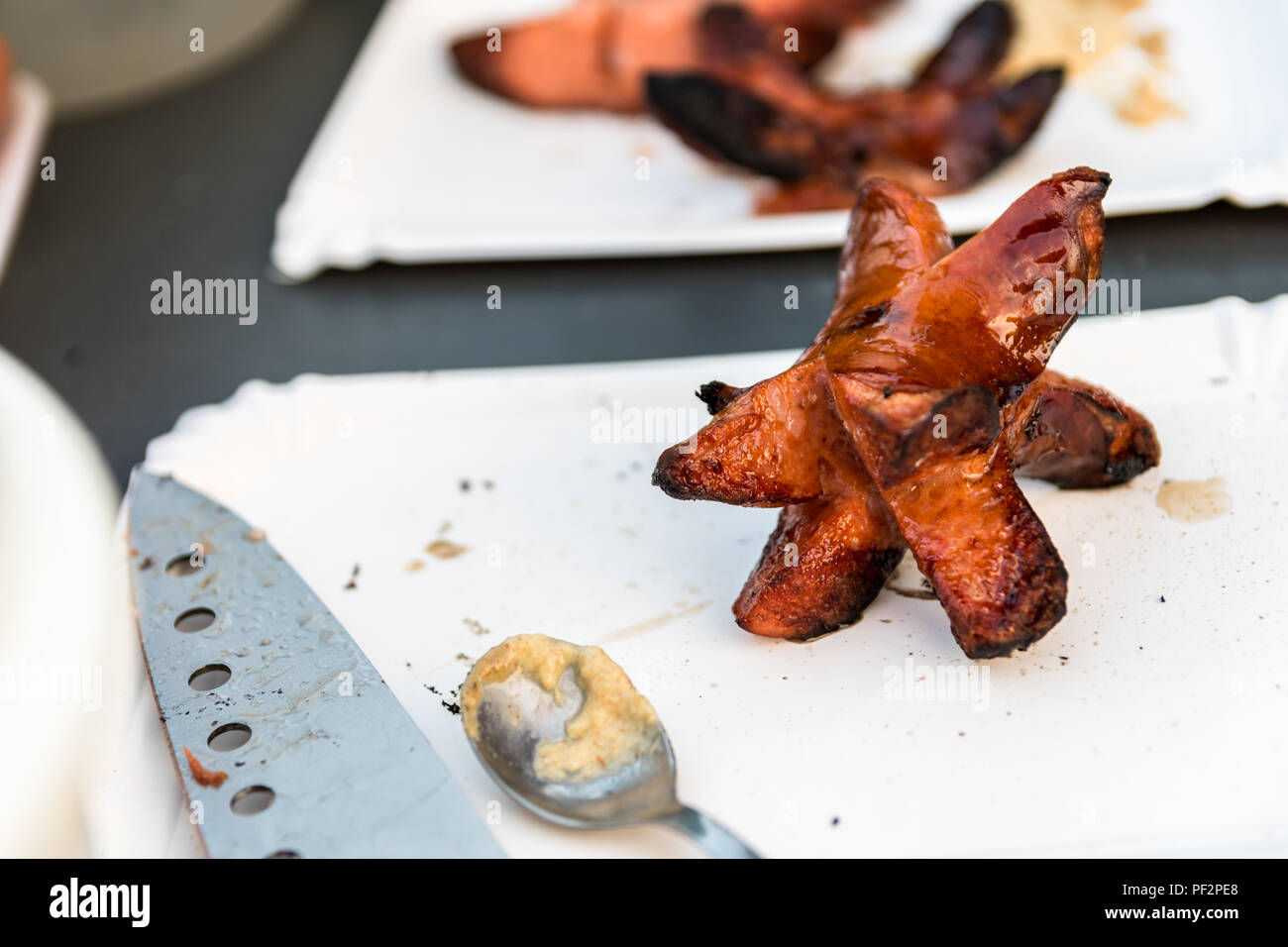 Preparing sausages in nature during a summer night. Unhealthy food. Sausage on a paper plate
