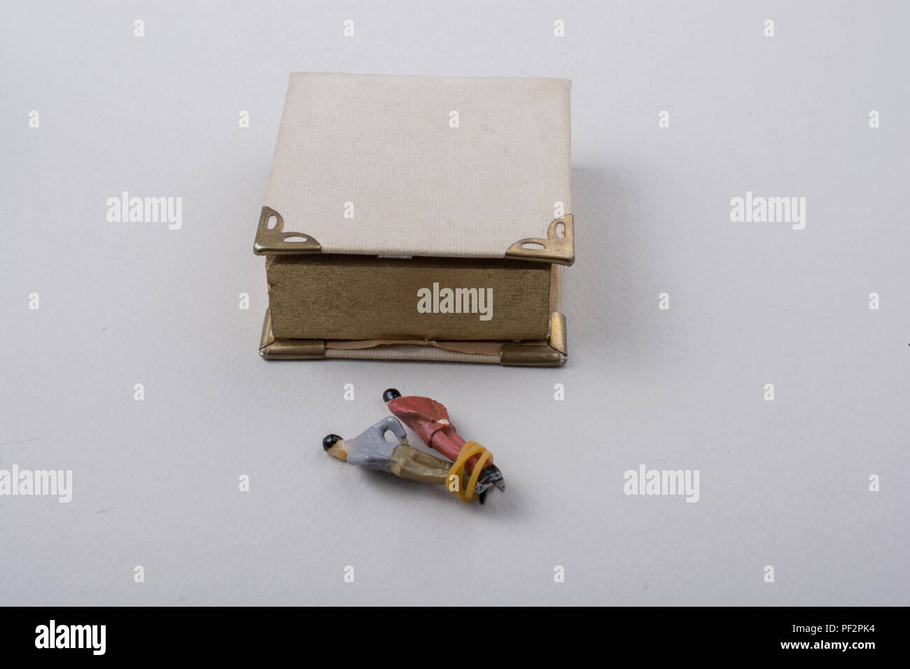 Tiny figurine of men model tied in rope beside a book Stock Photo - Alamy