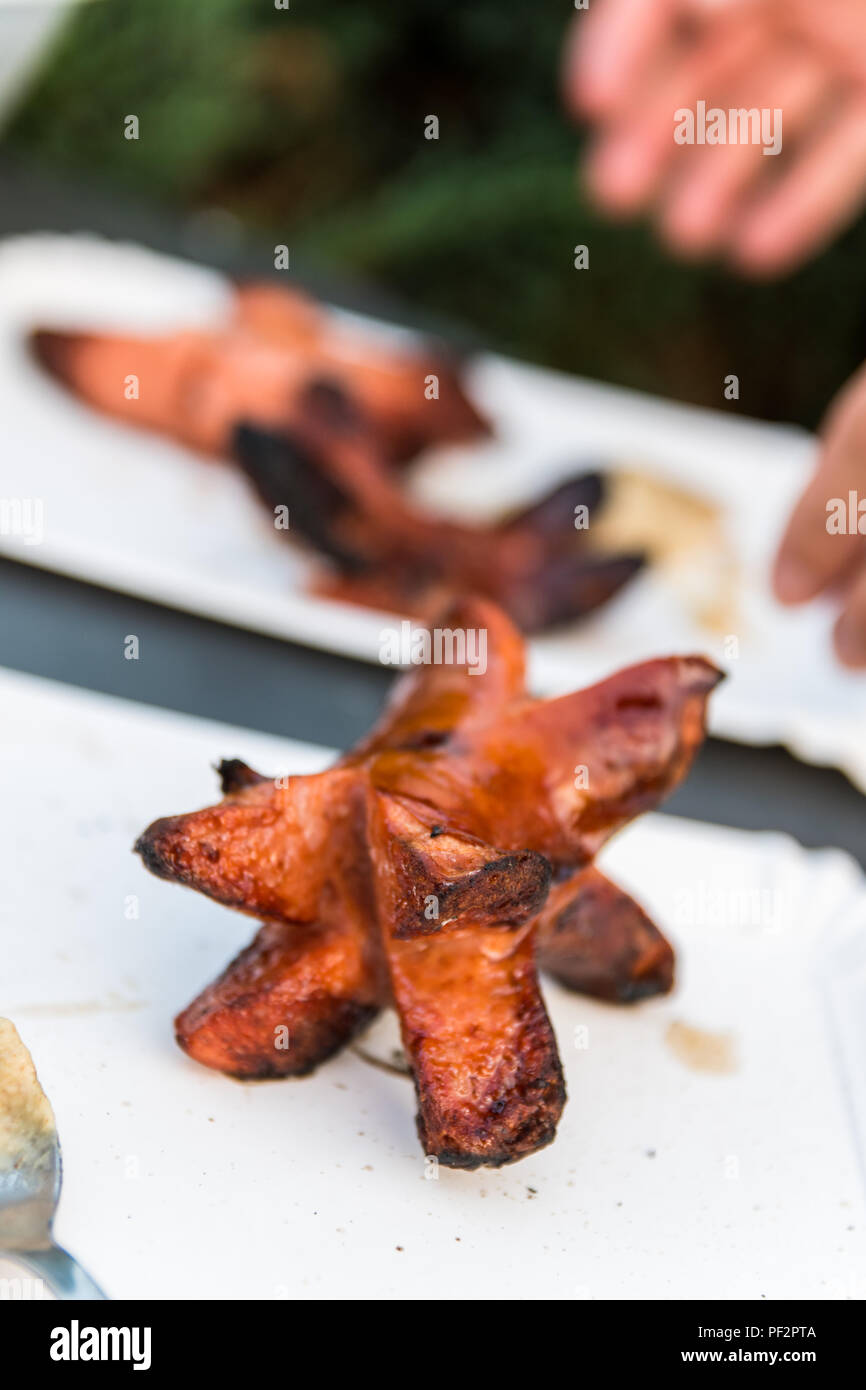 Preparing sausages in nature during a summer night. Unhealthy food. Sausage on a paper plate
