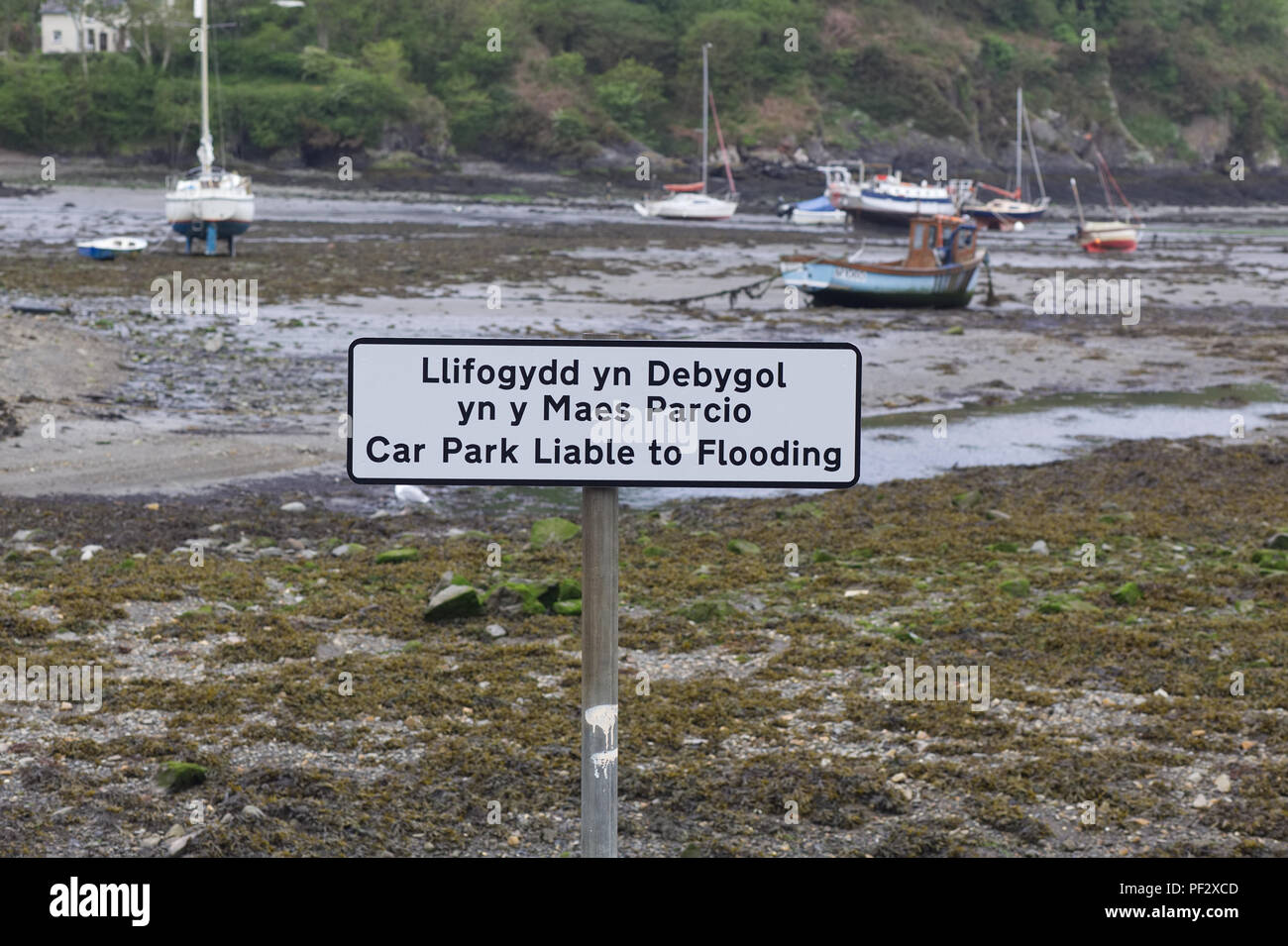 Boats in the harbor with a car park liable to flooding sign Stock Photo
