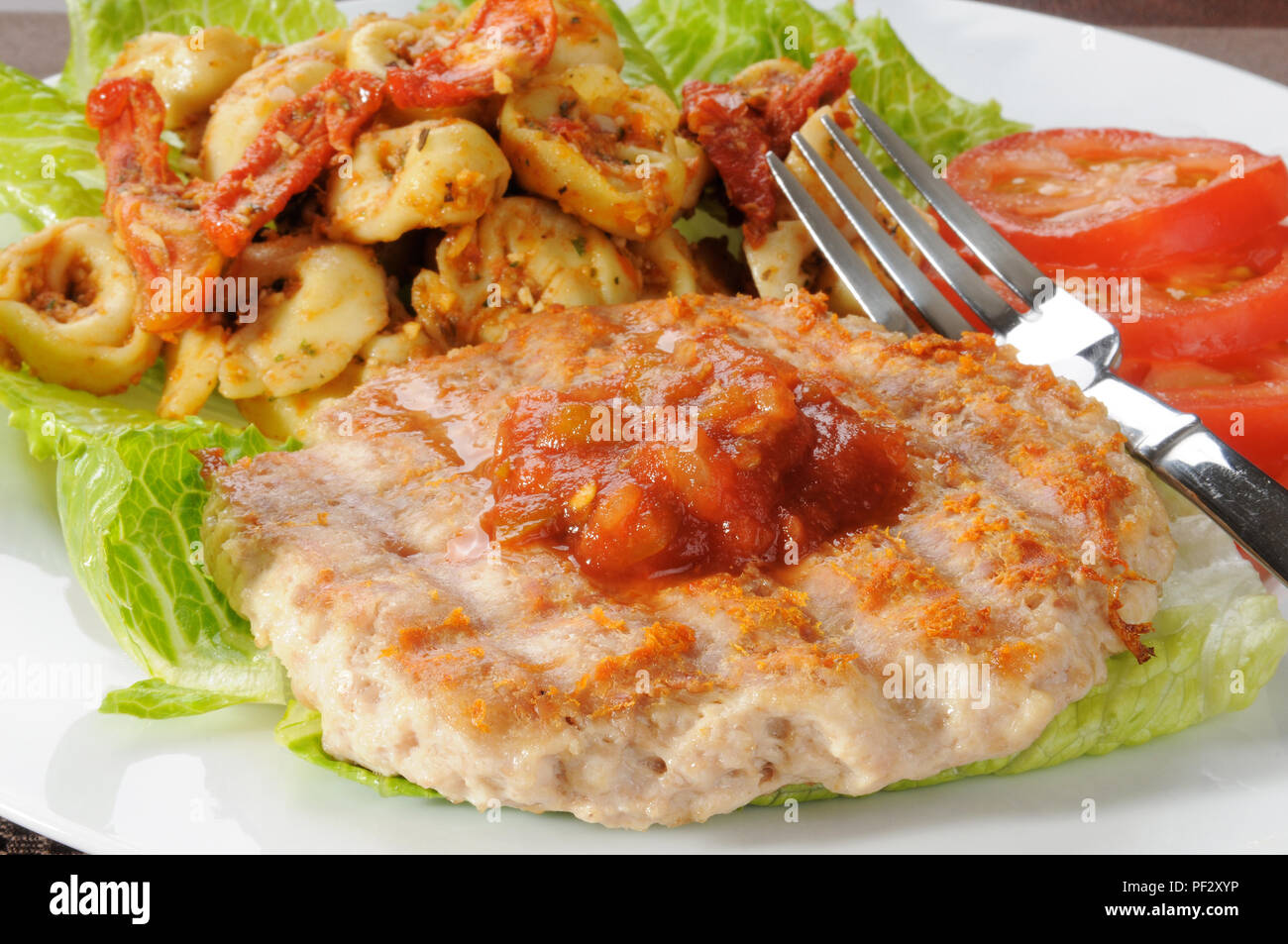 A grilled ground chicken or turkey patty with tortellini and roasted