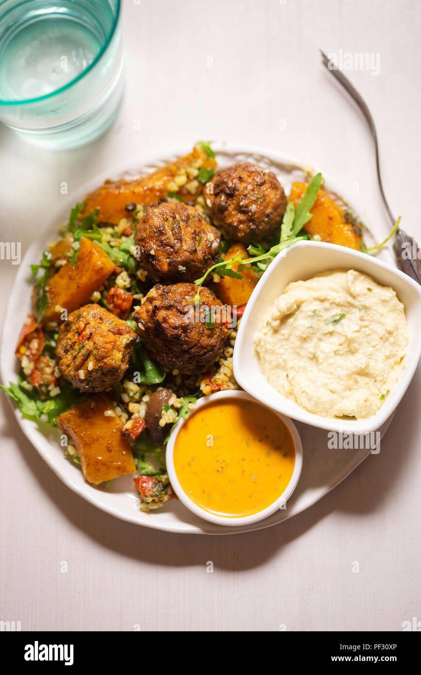Felafels with bulgur, rocket leaves, butternut squash salad & houmous & tahini lemon dressing Stock Photo