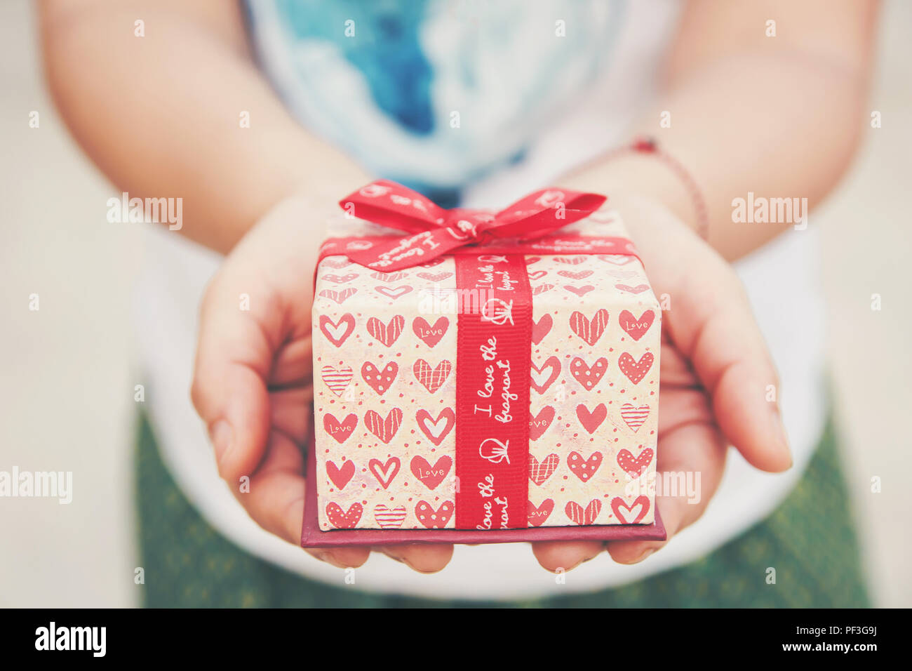 Close up female hand holding a small gift heart pattern. With red ribbon Stock Photo