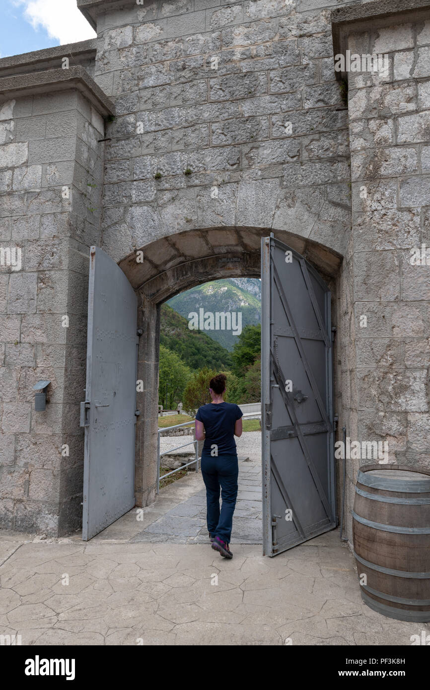 Woman exiting a prison or fort through iron gates Stock Photo