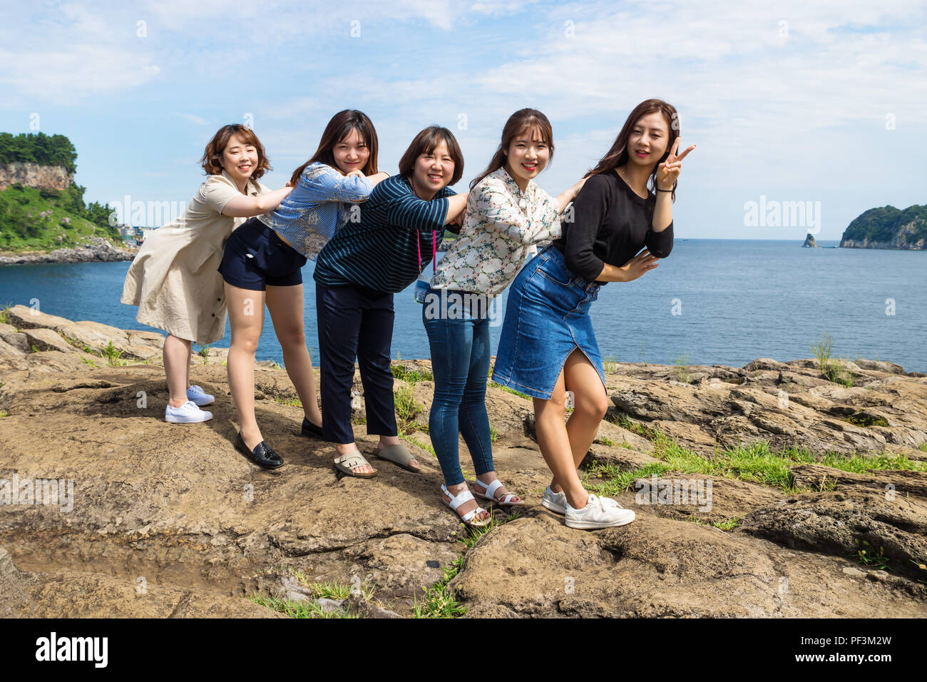 Five Korean tourist girls posing on the cliffs of Seogwipo, Jeju Island, South Korea Stock Photo