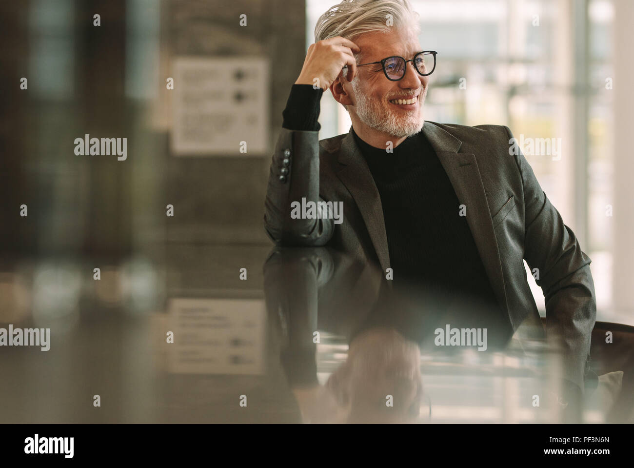 Senior business man relaxing at cafe. Mature man sitting at coffee shop counter and looking away smiling. Stock Photo