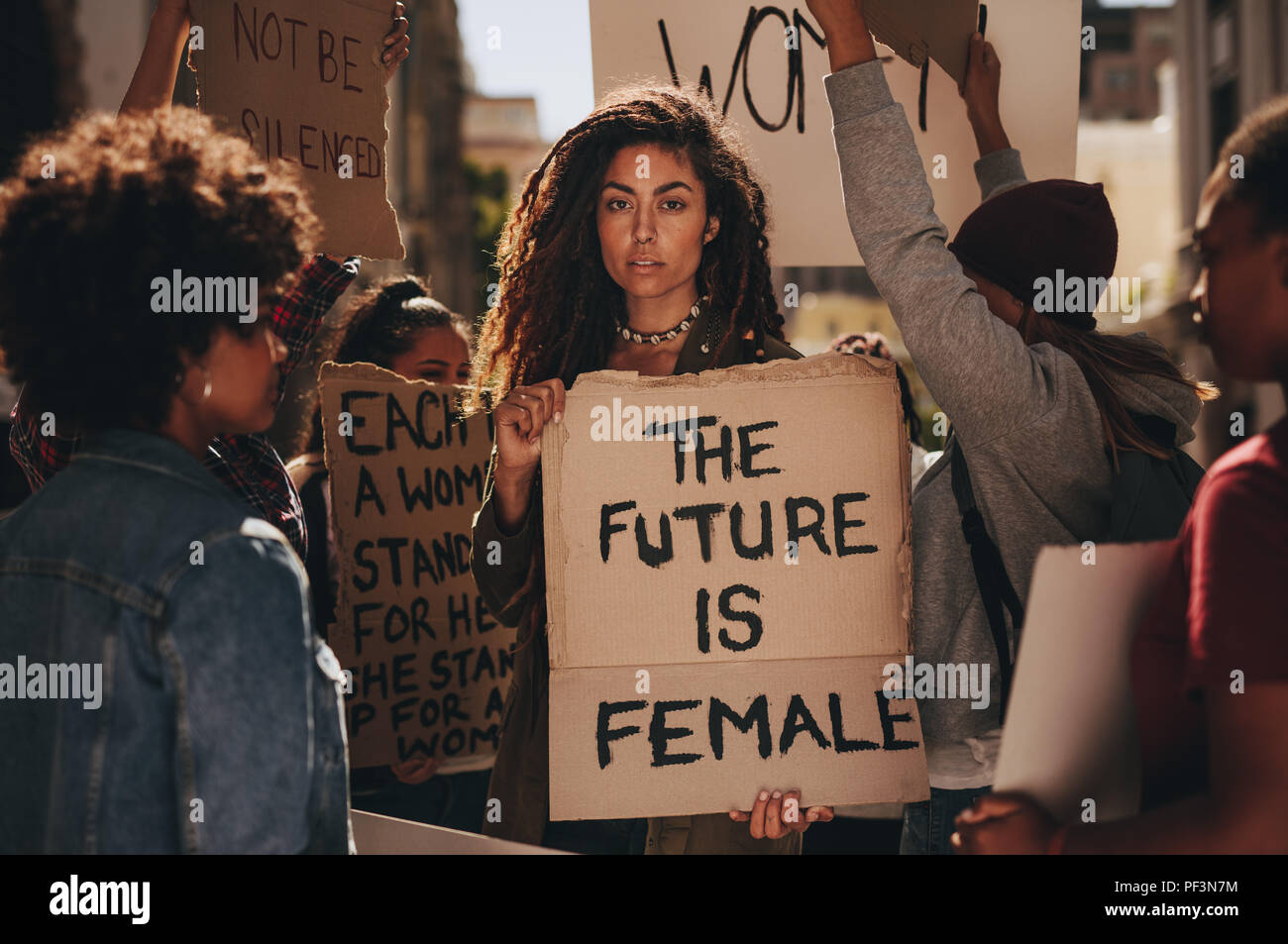 Woman holding a sing saying the future is female during a rally outdoors. Females protesting for their rights. Stock Photo