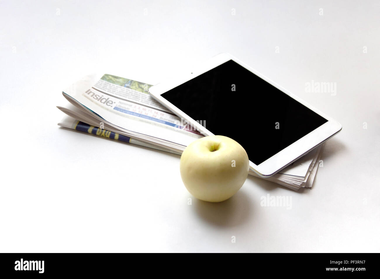 Digital tablet, folded newspaper and ripe apple on white background ...
