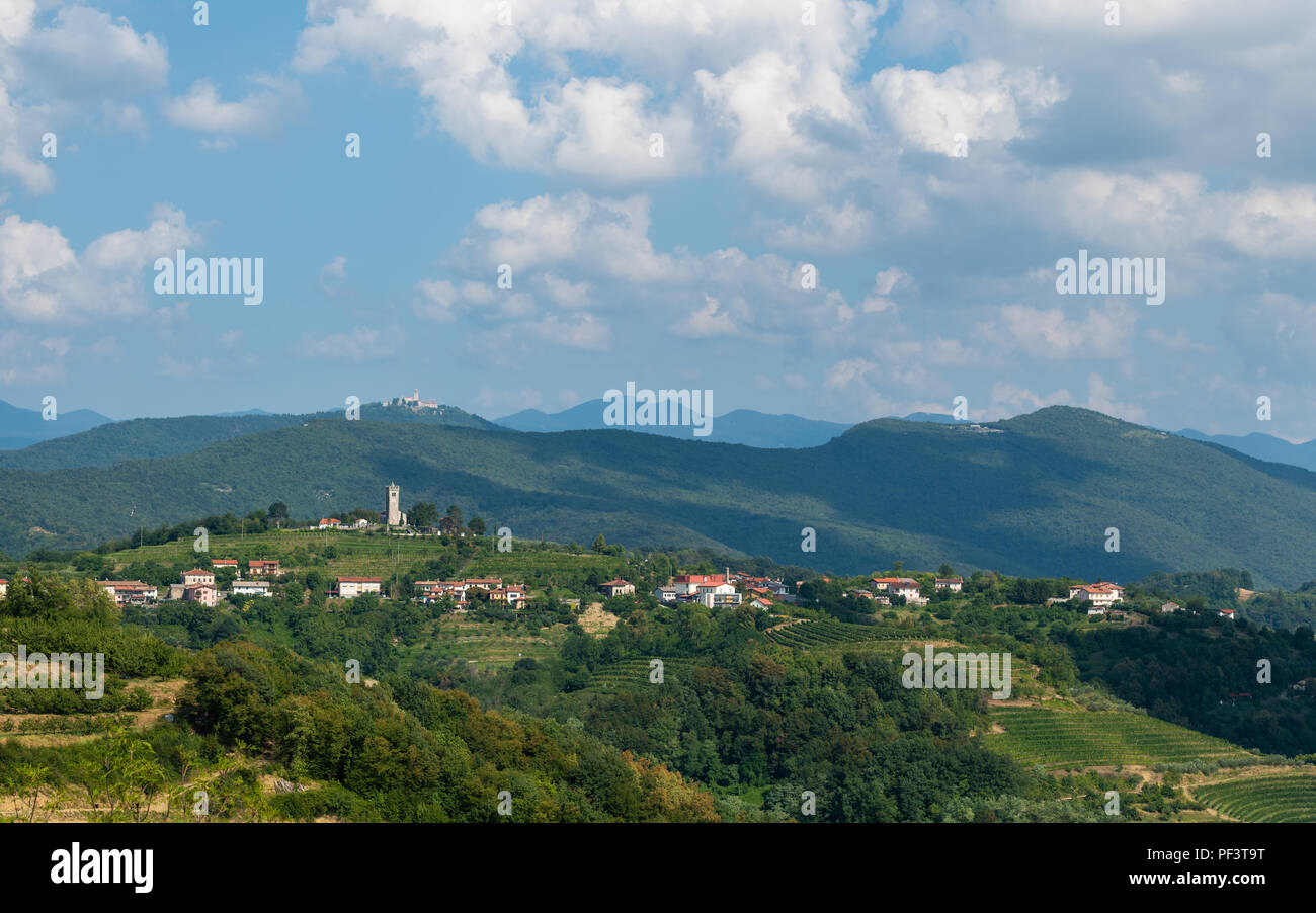 Village of Kojsko, Sloveniain famous wine growing region of Goriska Brda, lit by sun and clouds in background, holy mountain with church above Nova Gorica in background Stock Photo