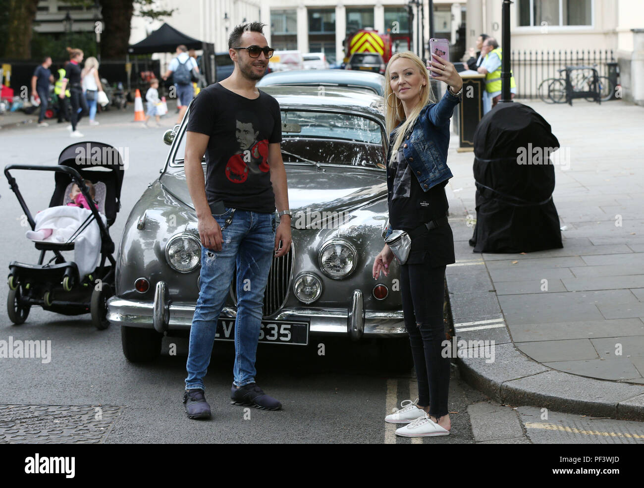 Visitors to Carlton Gardens photograph themselves in front of a vintage Jaguar Mark II parked amongst other classic vehicles as part of location filming for 'The Crown' in London. Stock Photo