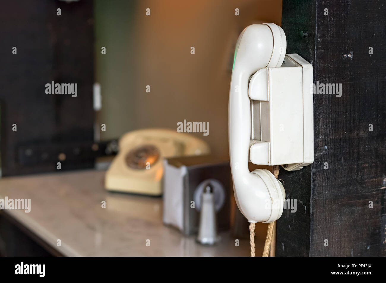 A vintage wall mounted intercom made with white plastic with a vintage telephone as a blurred background. Stock Photo