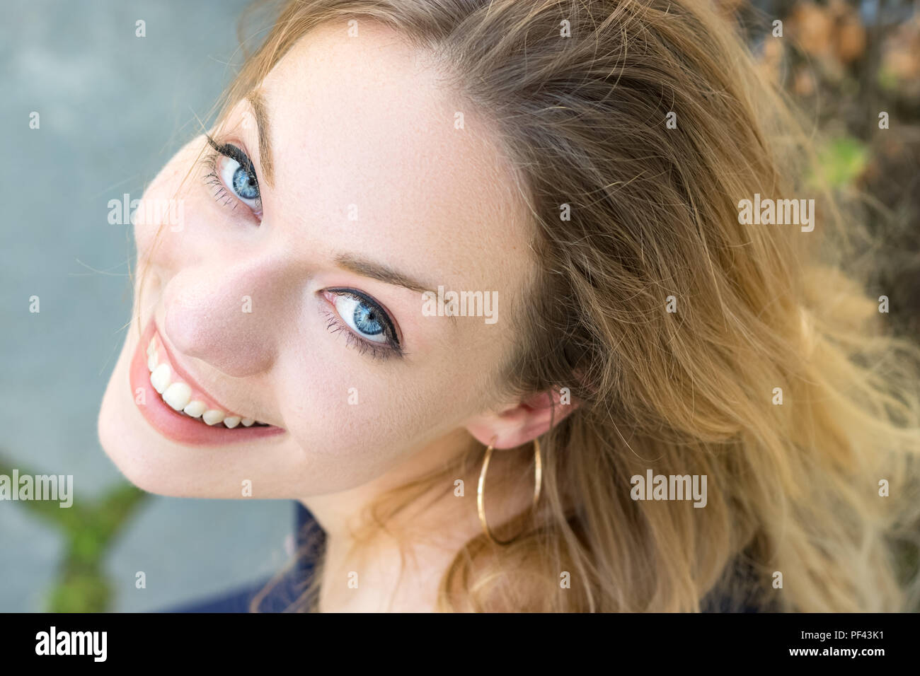 Portrait of an austrian young woman blonde with blue eyes looking up, toothy smile, healthy teeth. Stock Photo