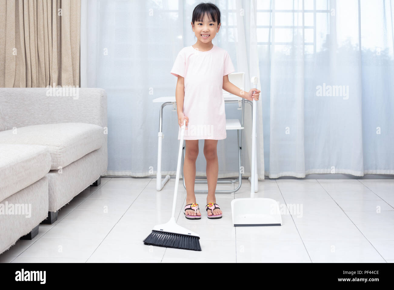 Asian Chinese little girl helping doing cleaning with broom and dustpan