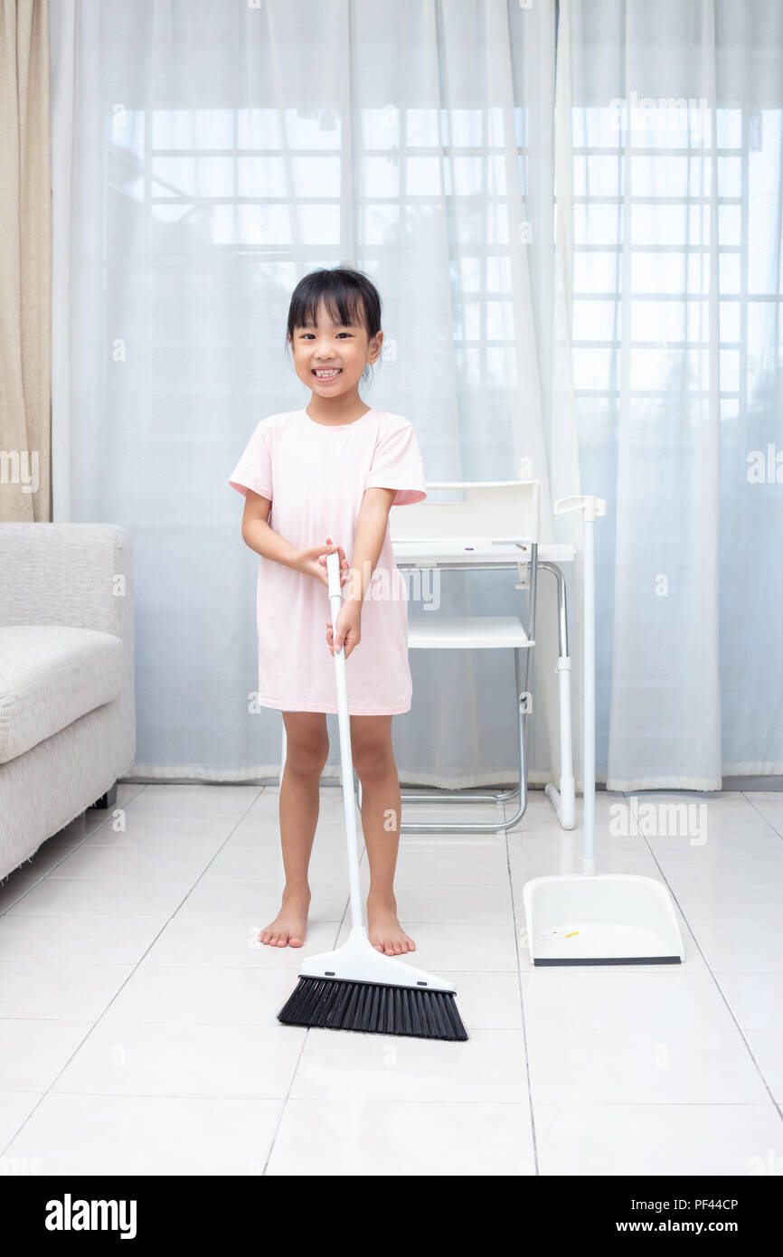 Asian Chinese little girl helping doing cleaning with broom and dustpan