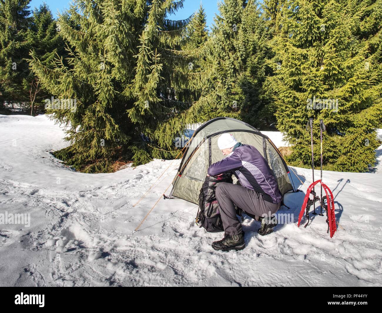 Camping in tent in winter forest. Snowshoes trek in mountains, setting