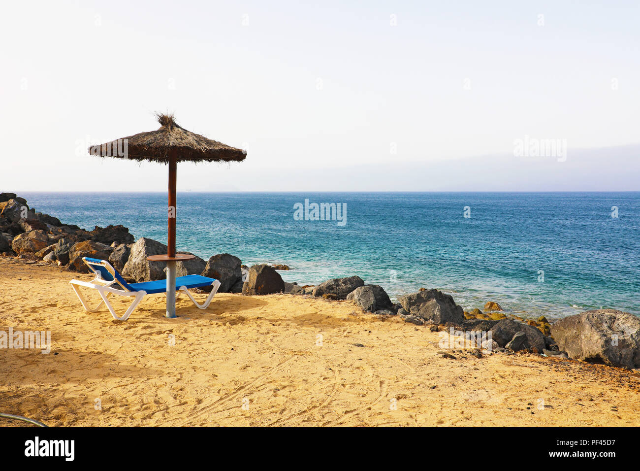 Beach umbrella and deck chair on a tropical beach of Lanzarote Stock Photo