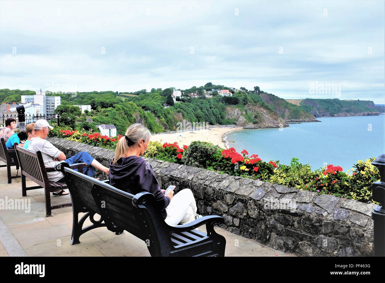 Tenby, Pembrokeshire, South Wales, UK. July 27, 2018.  Holidaymakers relaxing and enjoying the view over the South beach from High street at Tenby in  Stock Photo