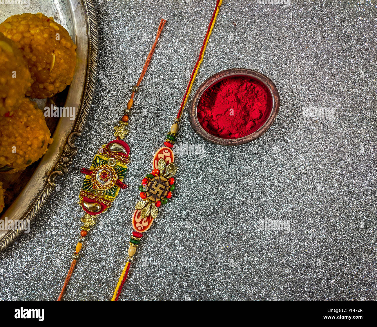 Rakhi with rice grains, kumkum and sweets on decorative plate and background with elegant Rakhi. A traditional Indian wrist band, symbol of love betwe Stock Photo