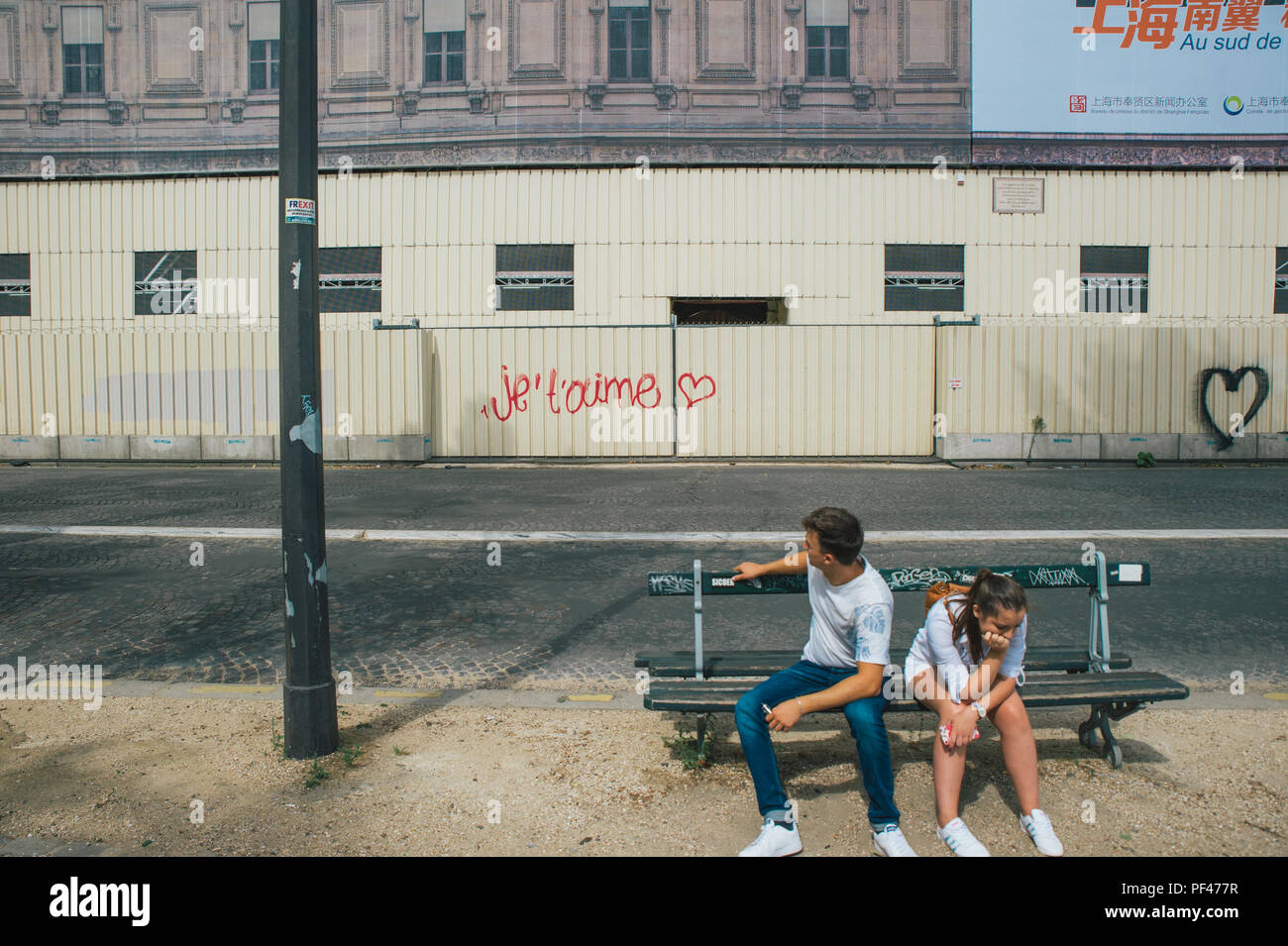 Young, french couple sitting in front of the je taime sign Stock Photo