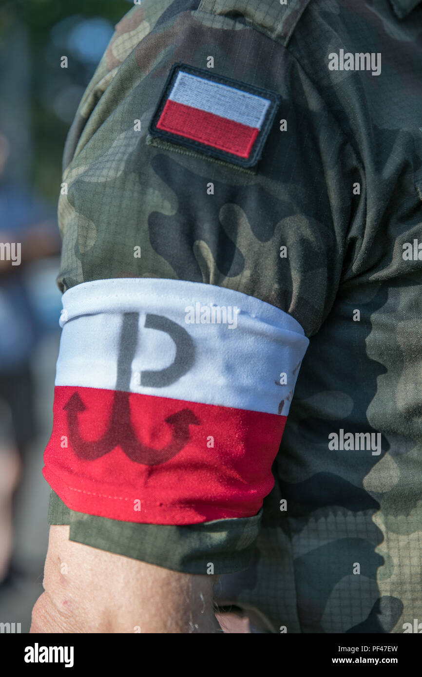 Arm of the soldier with white and red Polish flag with superposed anchor emblem of the Polish resistance. Anniversary of the Warsaw Uprising. Polish s Stock Photo