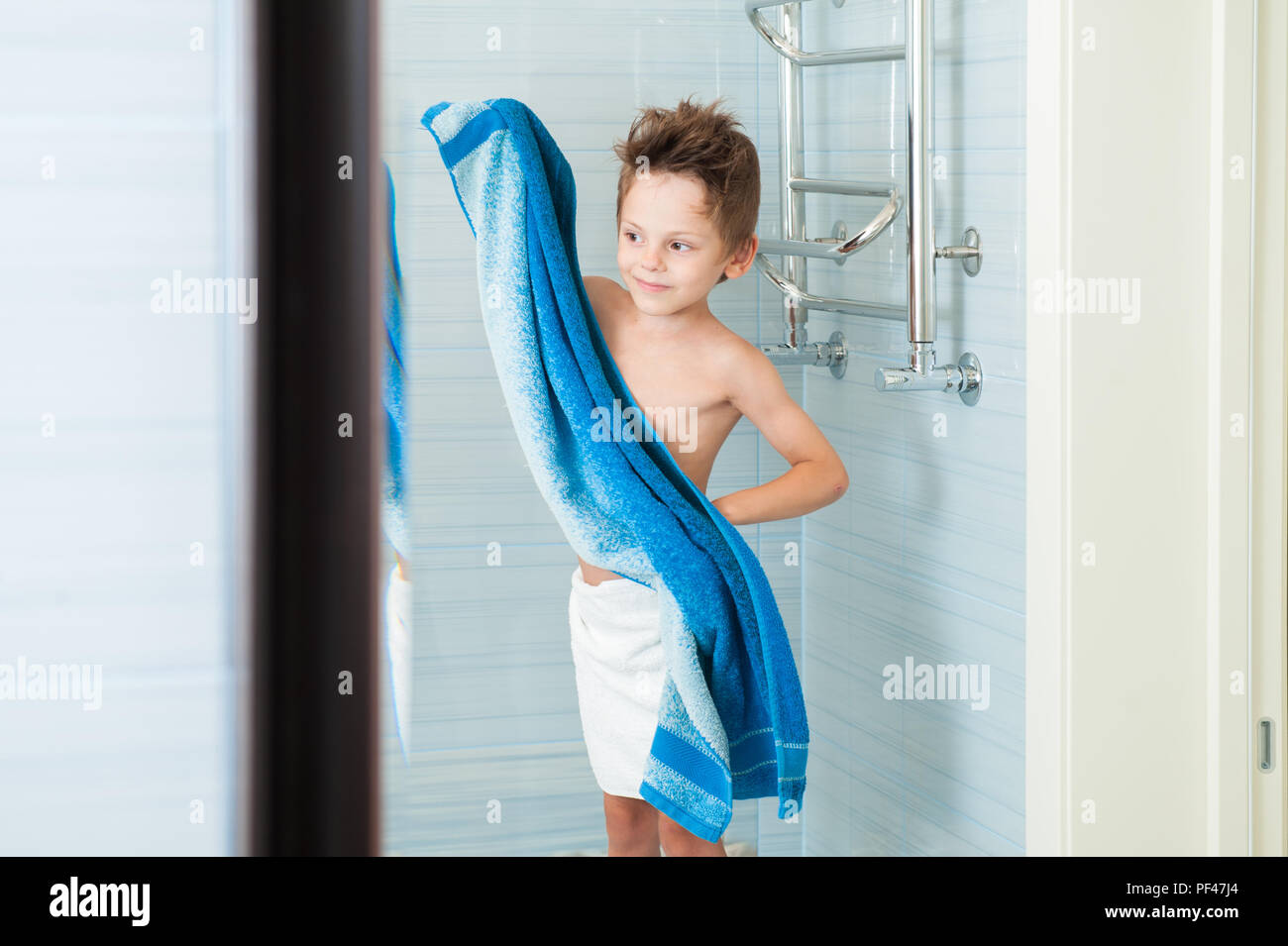 beautiful healthy kid dry off his clean body with blue towel in bright