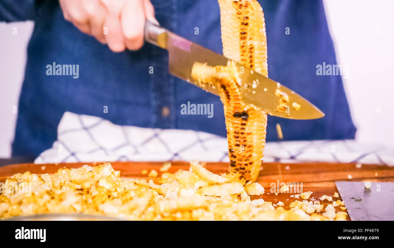 Step by step. Cutting the grilled corn of the cob ona wood cutting