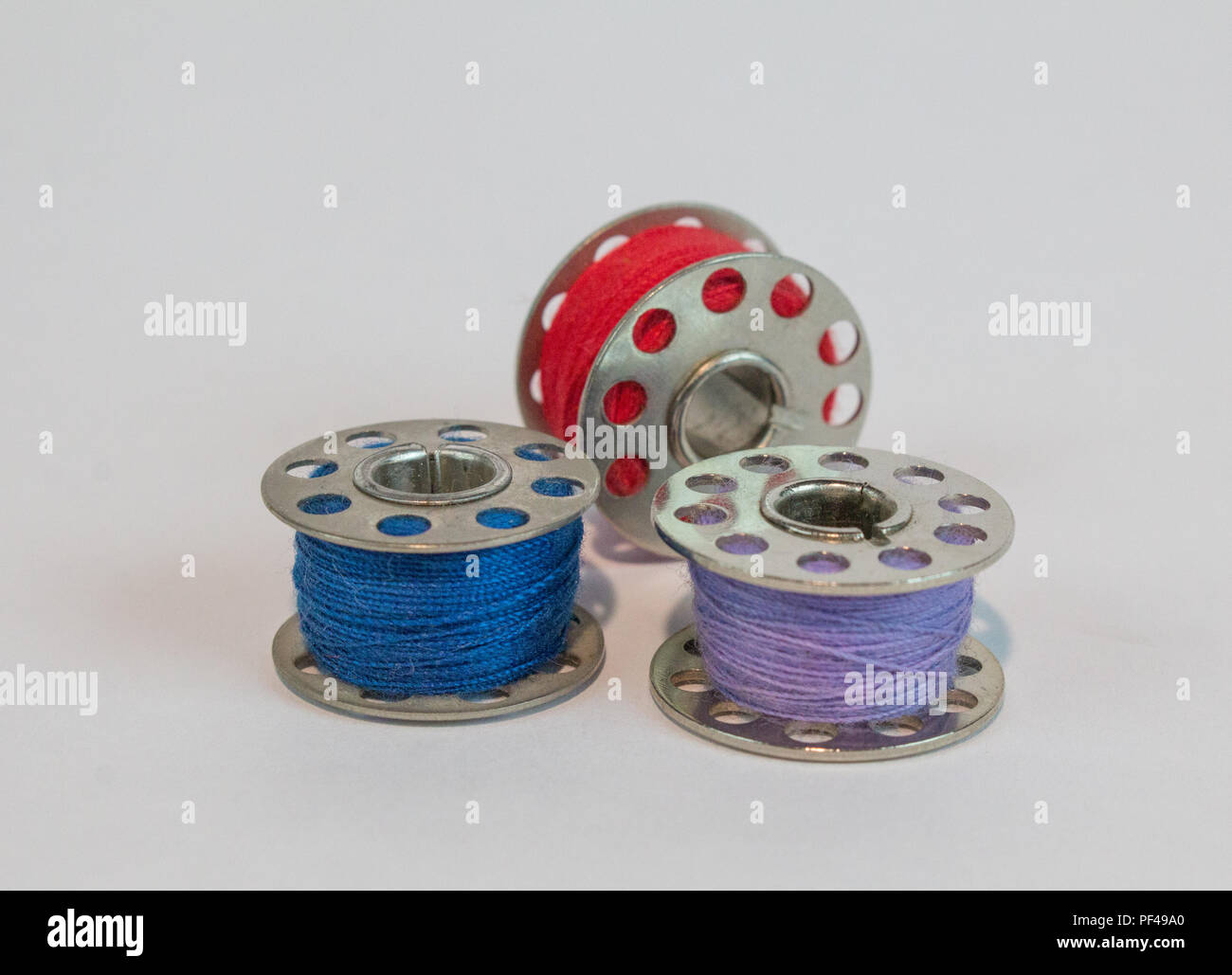 Three sewing machine bobbins with colorful thread Stock Photo - Alamy
