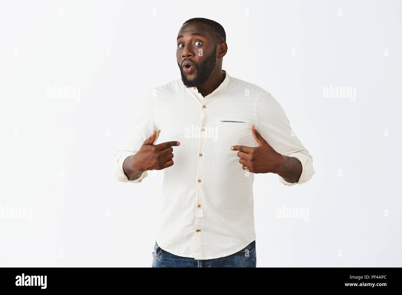 Whom me, no way. Portrait of surprised handsome dark-skinned male model in white shirt, pointing at himself and turning at camera with curious and questioned expression, being picked by someone Stock Photo