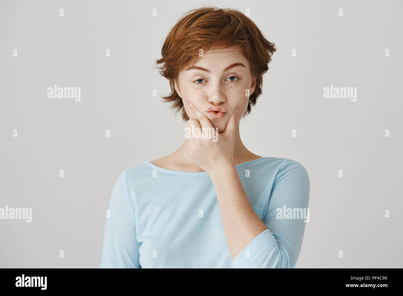Great detective solving new riddle. Portrait of funny redhead european girl  touching and squeezing chin, looking at camera with curious and thoughtful  expression, standing against gray background Stock Photo - Alamy