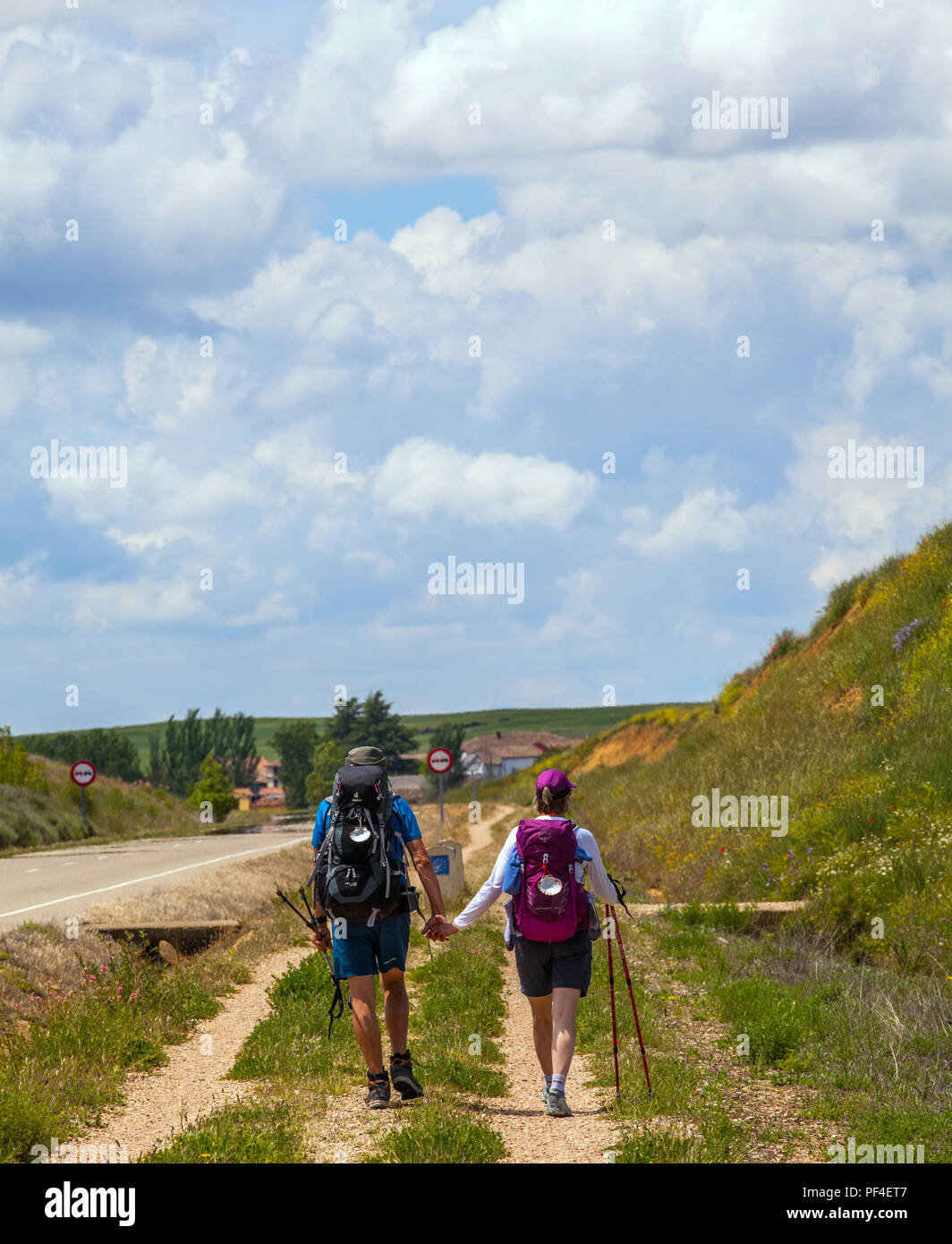 Couple man and woman walking hand in hand while walking the Spanish pilgrim route the Camino de Santiago the way of St James near Villalcazar de Sirga Stock Photo
