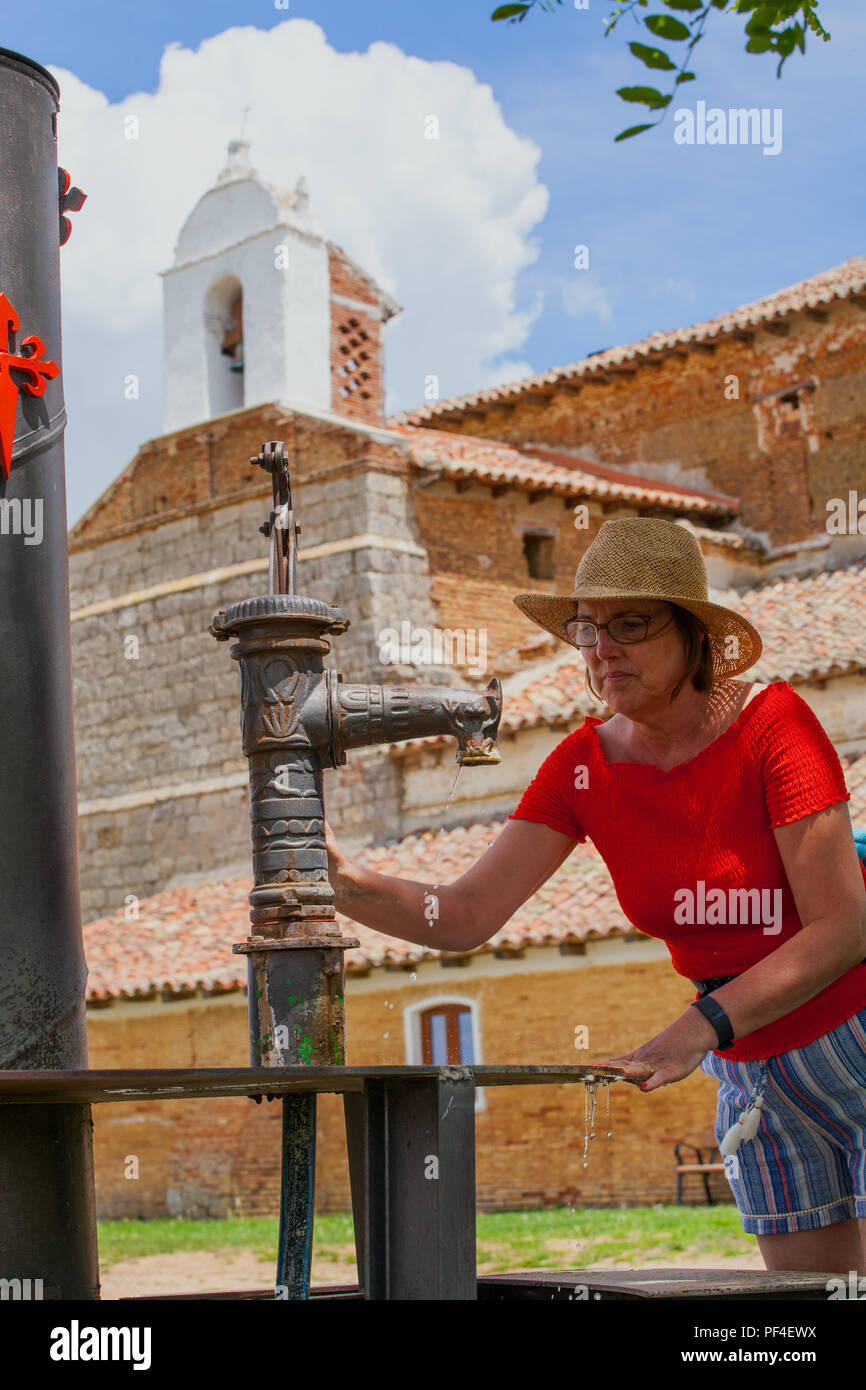 Woman using the water fountain at the Emita de la Virgin del rio while walking the Spanish pilgrim route the Camino de Santiago the Way of St James Stock Photo