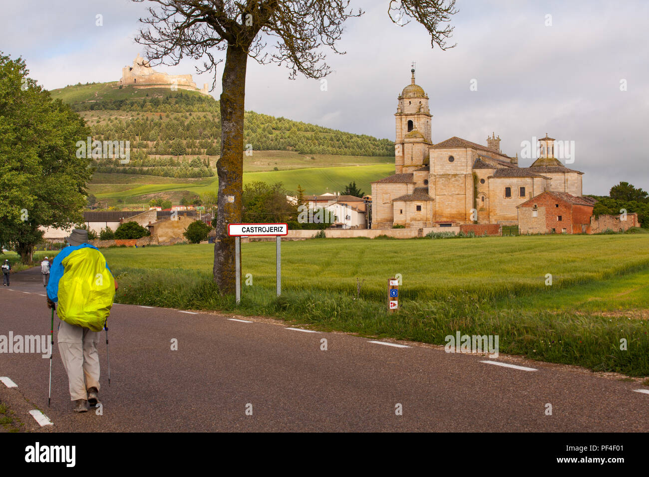 Pilgrims man approaching  the Spanish town of Castrojeriz with its Templar Castle while walking the Camino de Santiago pilgrimage route Spain Stock Photo