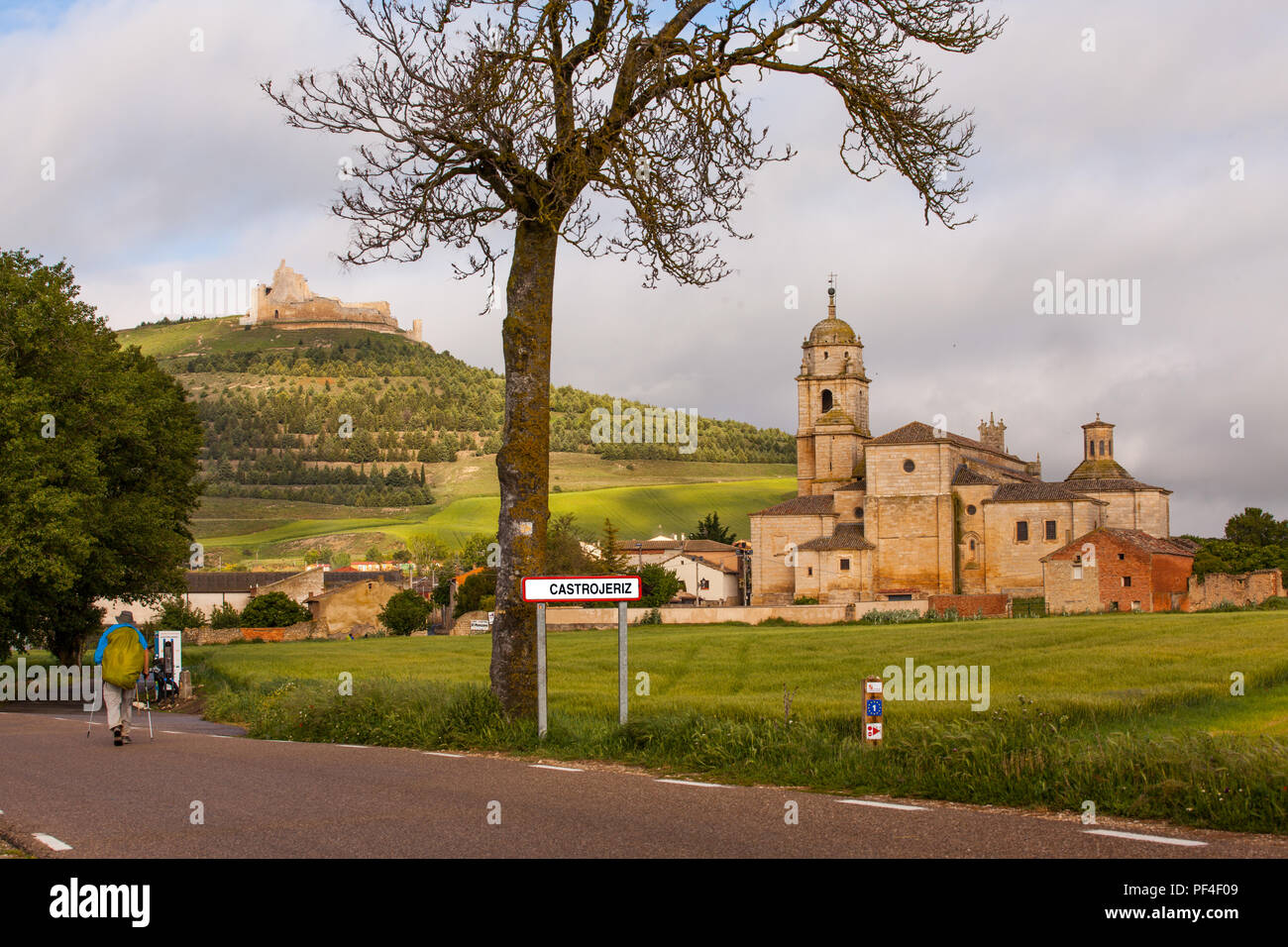 Pilgrims men and women approaching the Spanish town of Castrojeriz with its Templar Castle while walking the Camino de Santiago pilgrimage route Spain Stock Photo