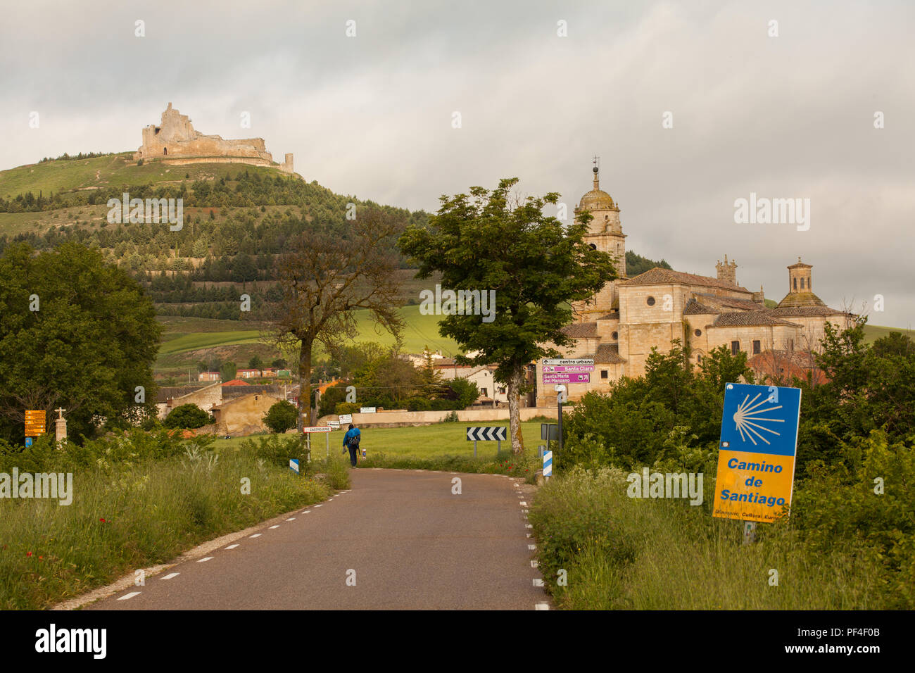 Pilgrim approaching the Spanish town of Castrojeriz with its Templar Castle while walking the Camino de Santiago pilgrimage route the way of St James Stock Photo
