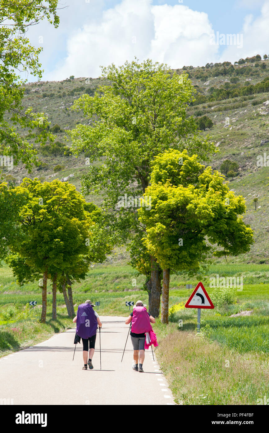 Pilgrims approaching the Spanish town of Castrojeriz with its Templar Castle while walking the Camino de Santiago pilgrimage route Spain Stock Photo