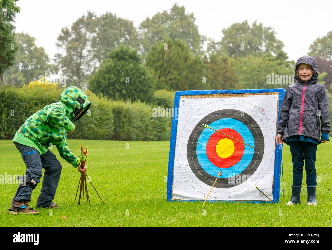 Haddington, UK. 19 August 2018.  The Royal Company of Archers, a ceremonial unit known as the Queen’s Bodyguard For Scotland stages a clout archery shoot as part of Haddington 700 events taking place during 2018 to celebrate the granting of a charter by Robert the Bruce to the town in 1318, confirming Haddington's right to hold a market and collect customs. Children also had a chance to try archery. A young girl points to her arrow which hit the target, and a young disabled boy with a leg brace for hemiplegia collects the arrows Stock Photo