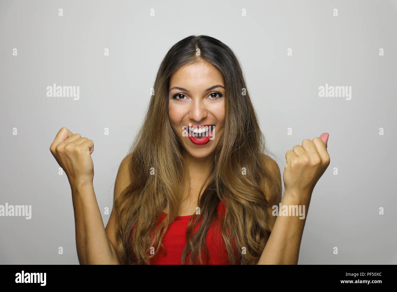 Happy successful young woman with raised hands shouting and celebrating ...