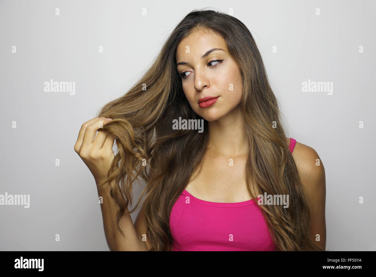 Attractive Young Woman Looking To Her Long Hair Beautiful Girl Looks Worried Satisfied At The Tips Of Her Hair On Gray Background Stock Photo Alamy