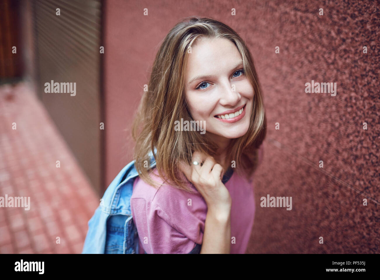 A blonde girl is smiling on a city street Stock Photo