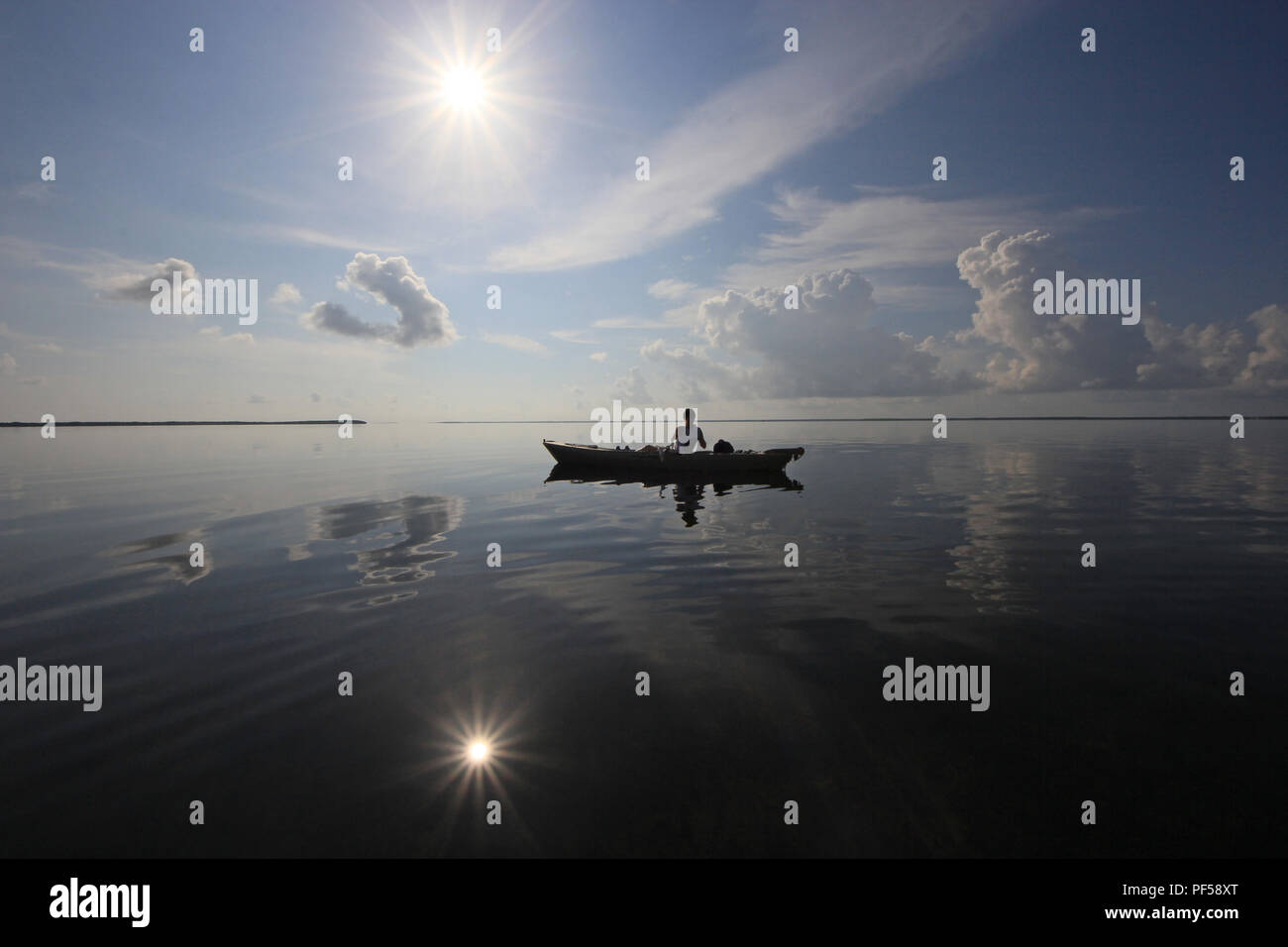 Woman kayaking on an exceptionally calm day with wonderful cloud reflections in Card Sound, Florida just west of Key Largo. Stock Photo