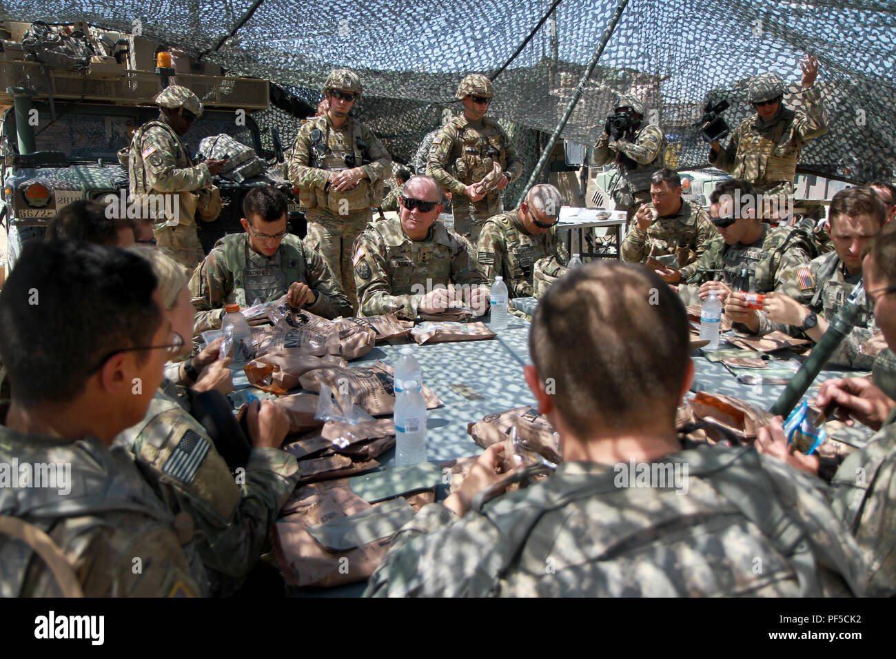 Lt. Gen. Timothy J. Kadavy (center), Director of the Army National Guard, joins the 112th Infantry Battalion, 56th Stryker Brigade Combat Team, 28th Infantry Division, Pennsylvania Army National Guard for a Meal Ready to Eat lunch in the field at the National Training Center, Fort Irwin, California Aug. 16. During their lunch, Kadavy discussed the importance of professional military education, leader development and having strong mentors within units. (U.S. Army National Guard photo by Cpl. Hannah Baker/released) Stock Photo