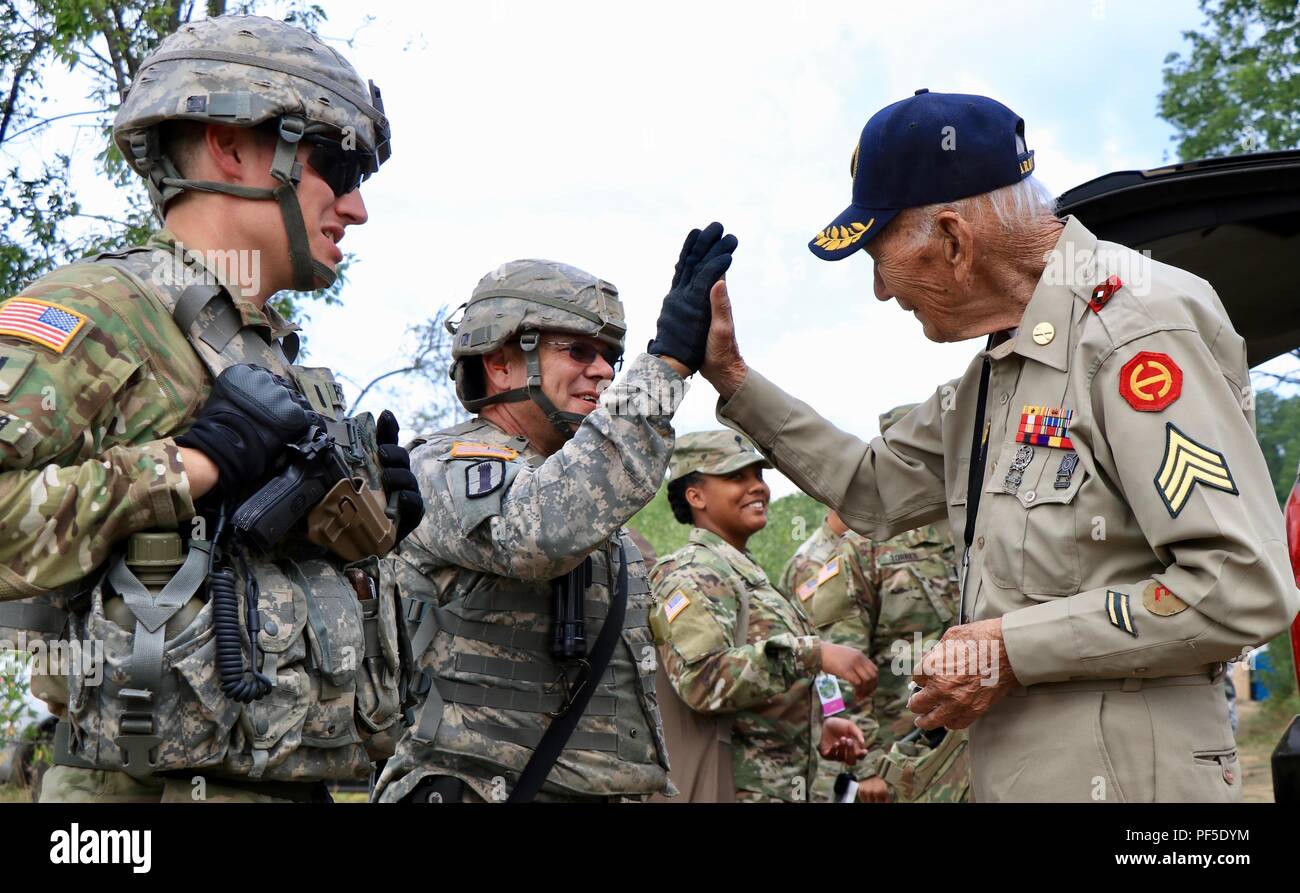 CAMP GRAYLING, Mich. - World War II veteran, Claude Cawood, gives Jeffery Lemire, first sergeant, Battery A, 1st Battalion, 103rd Field Artillery Regiment, Rhode Island Army National Guard a high-five after firing the M777 Howitzer, Aug. 9, 2018 at Camp Grayling, Mich. Cawood, a former section chief on the M105 Howitzer, who served three years in the Philippines had an opportunity to visit Soldiers supporting the Northern Strike exercise. (U.S. Army National Guard photo by 1st Sgt. Sara Robinson) Stock Photo