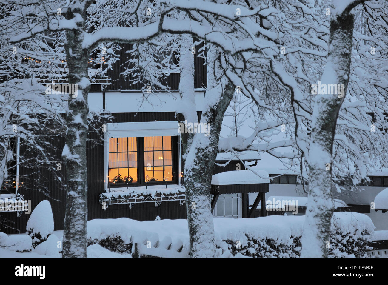 Haus beleuchtet mit Schnee bedeckt | house covered with snow and an illuminated window Stock Photo