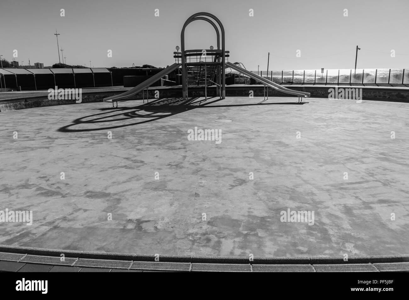 Swimming pool dry no water water slide structure deserted black and white. Stock Photo