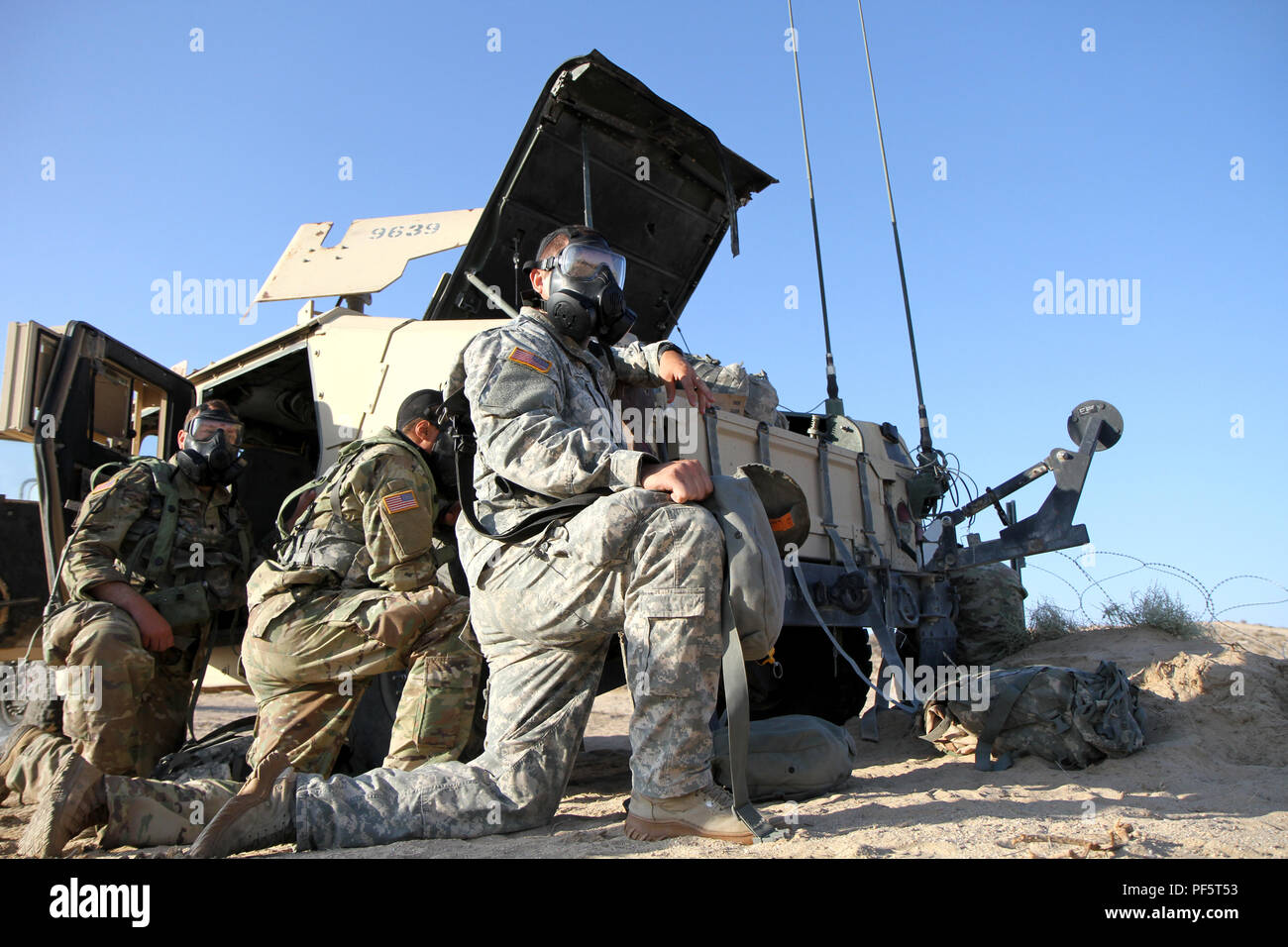 Soldiers with Delta Company, 103rd Brigade Engineering Battalion, 56th Stryker Brigade Combat Team, 28th Infantry Division, Pennsylvania Army National Guard, take cover as they wait for the “all clear” during an unexpected CS gas attack at the National Training Center, Fort Irwin, California, Aug. 17. Ability to react quickly to a Chemical, Biological, Radiological and Nuclear hazard assures that Army National Guard Soldiers maintain the readiness standards set forth by the Army’s Total Force Policy and support the National Defense Strategy. (U.S. Army National Guard photo by Sgt. 1st Class Ho Stock Photo